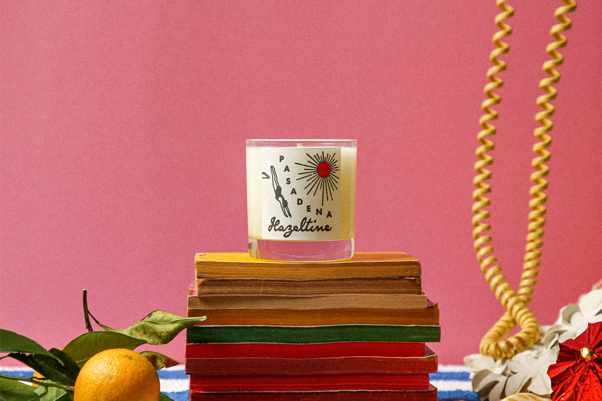 Hazeltine Pasadena candle on stacked vintage books against a pink backdrop.